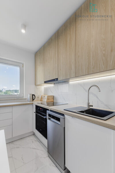 Modern L-shaped kitchen with white lower cabinets, light wood upper cabinets, and marble backsplash.