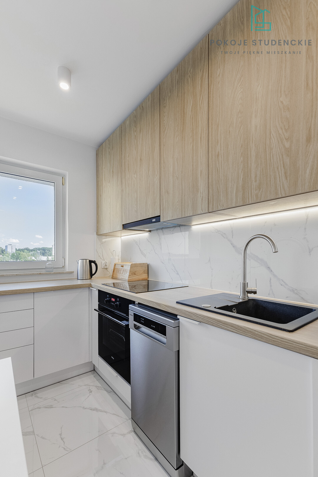 Modern L-shaped kitchen with white lower cabinets, light wood upper cabinets, and marble backsplash.
