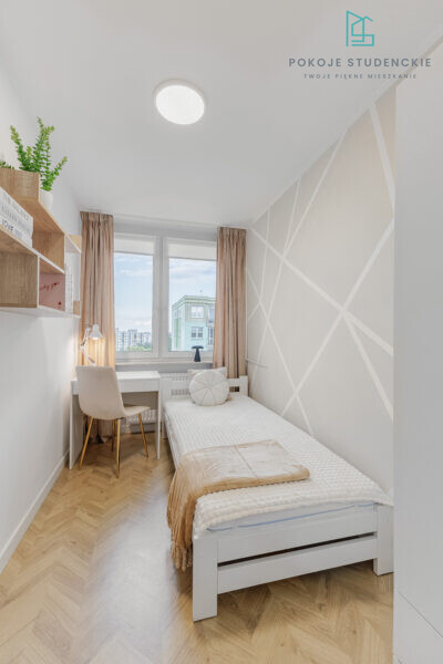 Small bright student room with white furniture, single bed, desk, shelves, and geometric wall pattern by the window.
