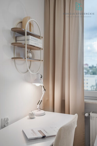 Modern study nook with a wall shelf, white desk lamp, and beige curtains by a window; decorative owl and stacked books add a cozy touch.