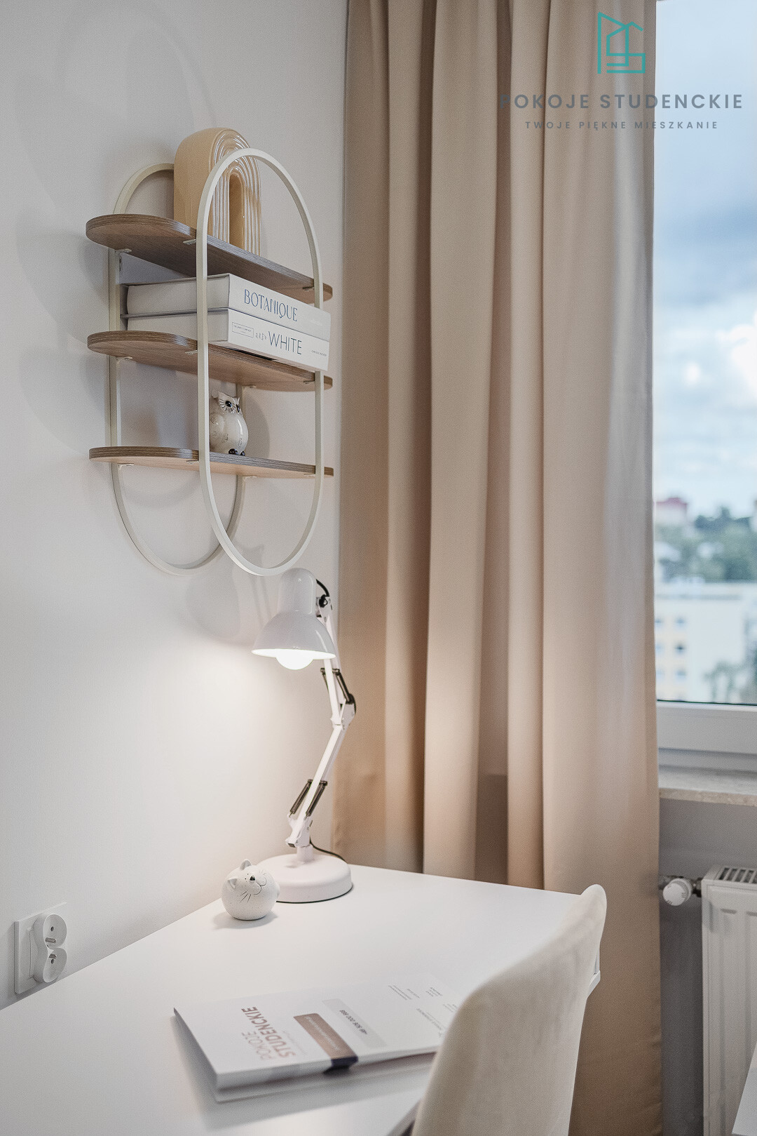 Modern study nook with a wall shelf, white desk lamp, and beige curtains by a window; decorative owl and stacked books add a cozy touch.