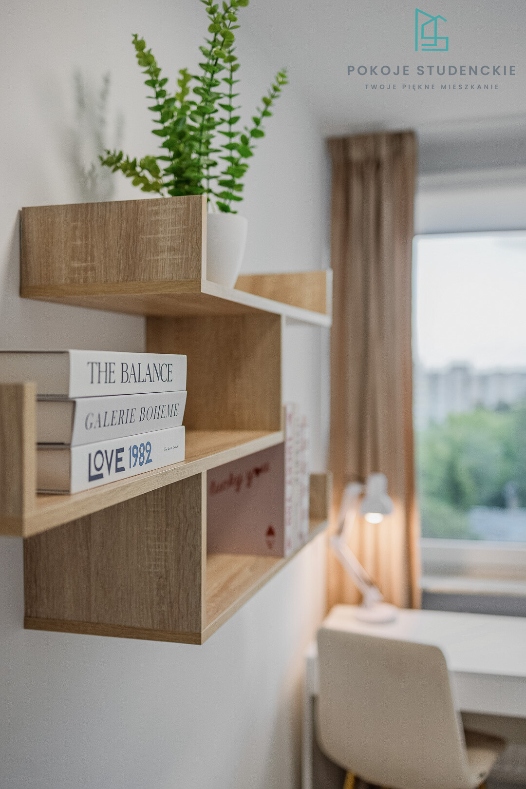 Wooden wall shelf with a potted green plant and stacked books, in a tidy, sunlit room near a window.