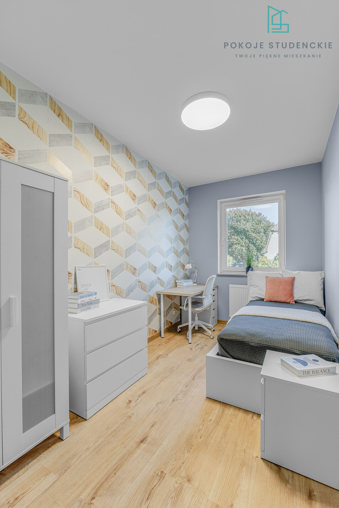 Small modern bedroom with a geometric patterned wallpaper on the left wall, light blue walls, white furniture, and a single bed by a window.